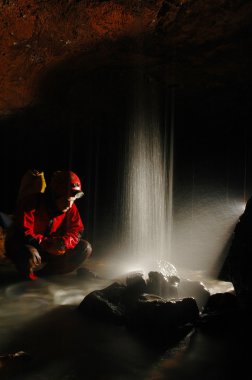 Caver with a small waterfall clipart