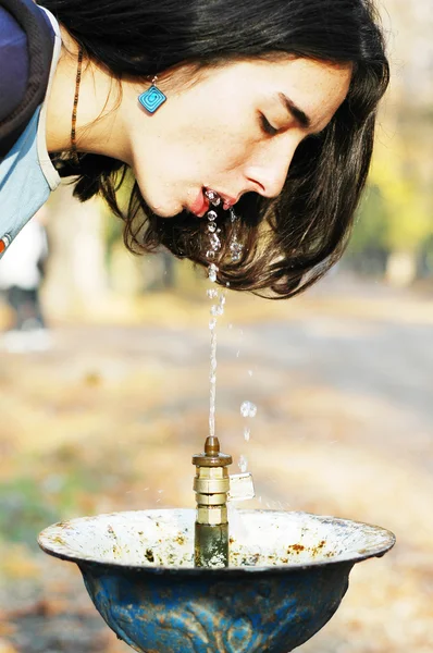 Una giovane bella ragazza caucasica beve da una fontana pubblica — Foto Stock