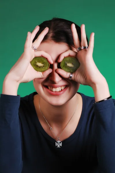 stock image Pretty young woman holds kiwi in front of her eyes