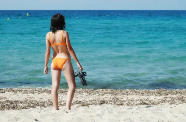Frau im orangefarbenen Bikini mit Flops am Strand — Stockfoto