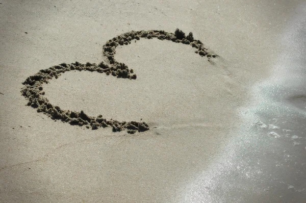 Coração escrito à mão na areia com onda se aproximando — Fotografia de Stock