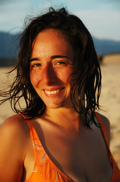 Vacker leende flicka på en strand med sena eftermiddagen lampor — Stockfoto