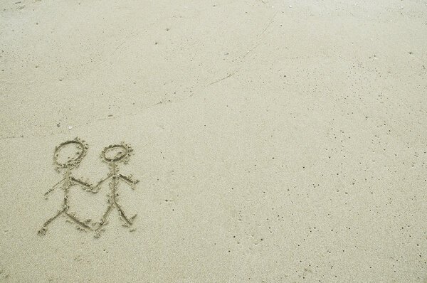 Просто пара рисует в песке на пляже
