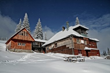 Snow covered mountain holiday house at winter clipart