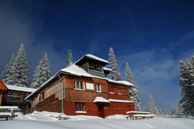 Snow covered mountain holiday house at winter clipart