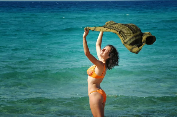 Schöne junge Frau am Strand mit einem farbigen Gewebe — Stockfoto
