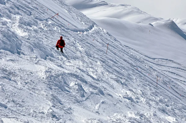 Esqui descendo a montanha em uma encosta em um dia ensolarado — Fotografia de Stock