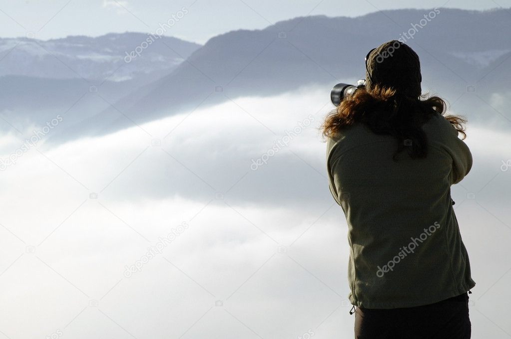 Woman photographing above clouds