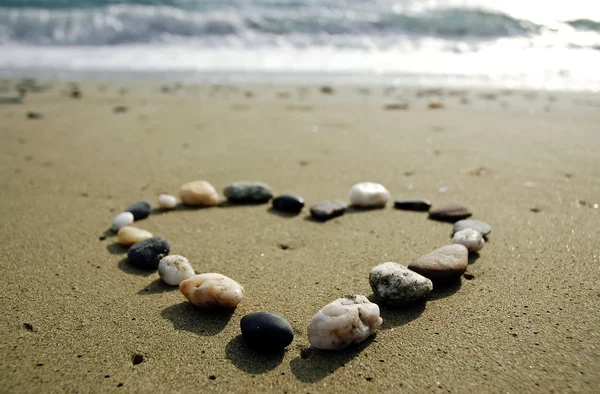 Coração feito de pequenas pedras na areia — Fotografia de Stock