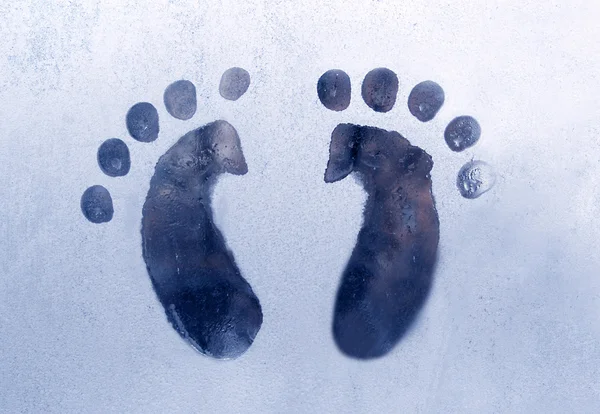 Feet traces on a frozen window blue