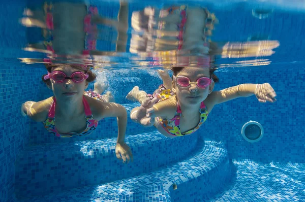 Niños felices sonriendo bajo el agua en la piscina —  Fotos de Stock