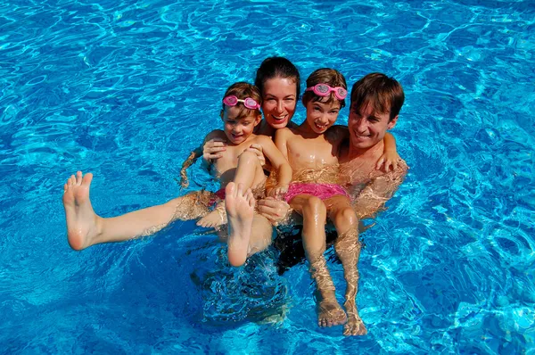 Família feliz de quatro se divertindo na piscina — Fotografia de Stock