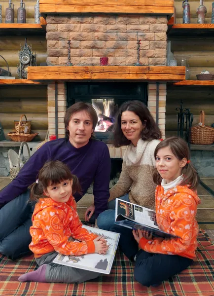 Gelukkige familie plezier in de buurt van open haard in houten huis — Stockfoto