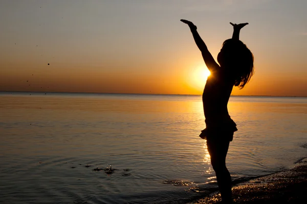 Kindersilhouette am Strand bei Sonnenuntergang, kleines Mädchen hat Spaß — Stockfoto