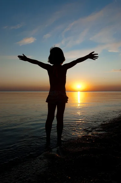Kindersilhouette am Strand bei Sonnenuntergang, kleines Mädchen hat Spaß — Stockfoto