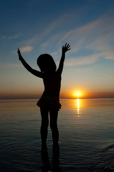 Silueta dítěte na pláži při západu slunce, holčička baví — Stock fotografie