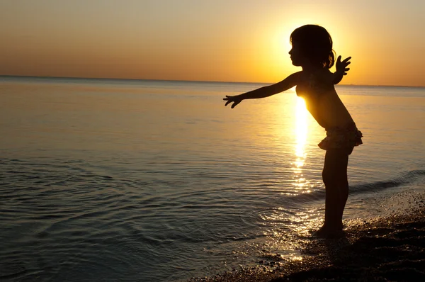 Barn siluett på sunset beach, liten flicka ha kul — Stockfoto
