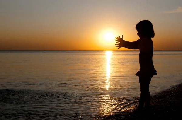 Sylwetka dziecka na zachód słońca plaża, mała dziewczynka zabawy — Zdjęcie stockowe