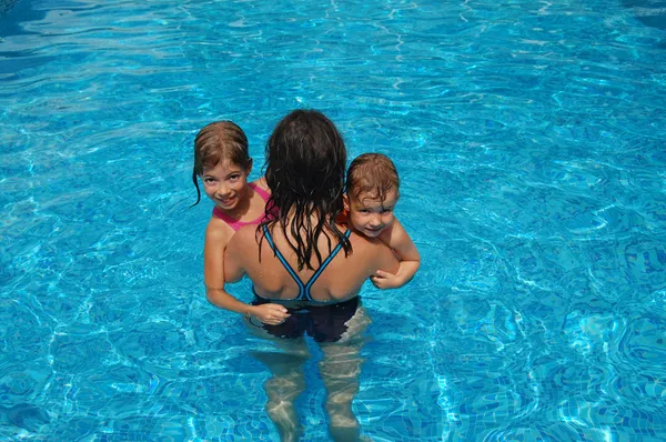 stock image Happy active mother with kids in swimming pool