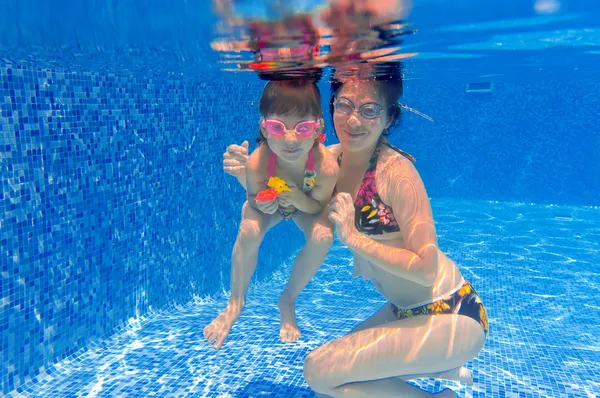 Familia sonriente bajo el agua divirtiéndose y jugando en la piscina —  Fotos de Stock
