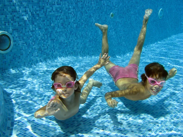 Niños felices sonriendo bajo el agua en la piscina — Foto de Stock