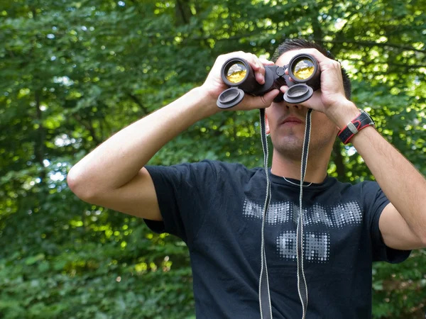Young man looking through binoculars — Stock Photo, Image
