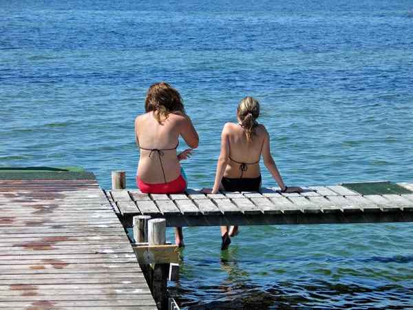 stock image Two girls sit and relax on a dock