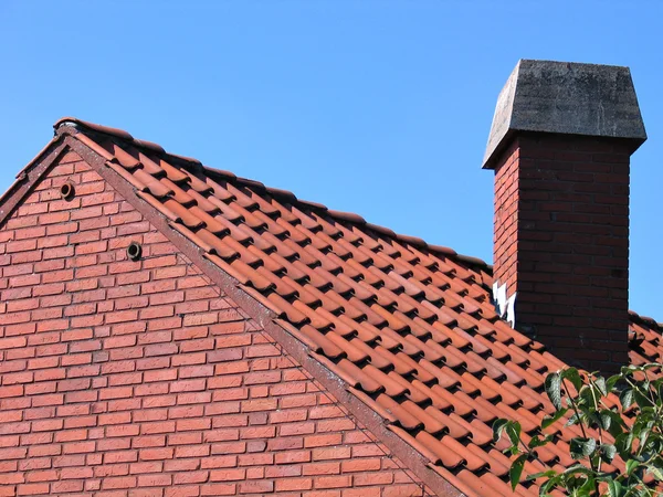 Крыша с красной черепицей и дымоходом — стоковое фото