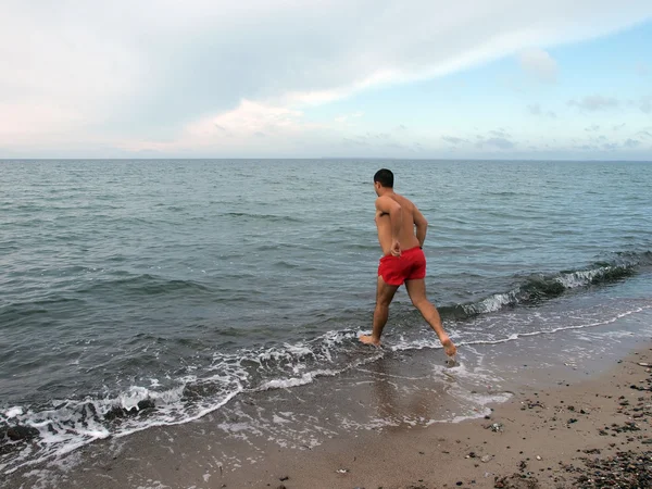 Gelukkig man loopt in de zee te zwemmen — Stockfoto