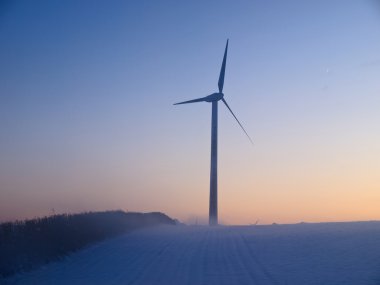 Alternative energy wind mills in the snow clipart