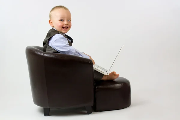 Happy baby in leather Chair with Laptop — Stock Photo, Image