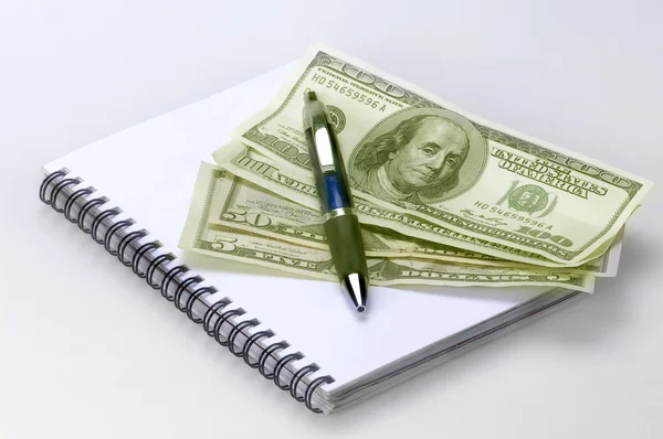 Δολάρια σε λευκό φόντο με το σημειωματάριο και στυλό δίνει σημειογραφία — Φωτογραφία Αρχείου