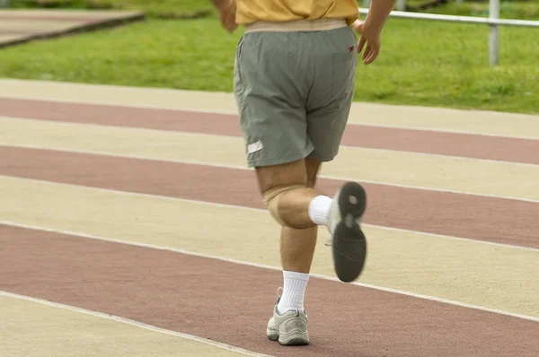 Adult man running on athletics track — Stock Photo, Image