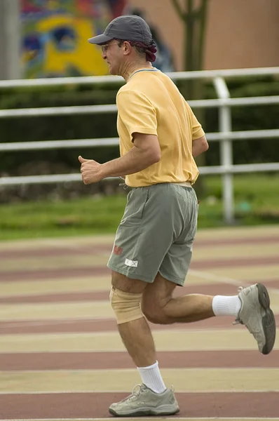 Hombre adulto corriendo en pista de atletismo —  Fotos de Stock