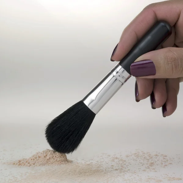 Pó e escova de maquiagem com mão feminina — Fotografia de Stock