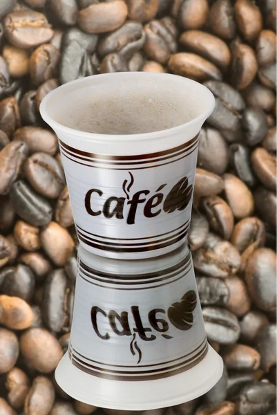 Tazze di plastica con chicchi di caffè sfondo caffè — Foto Stock