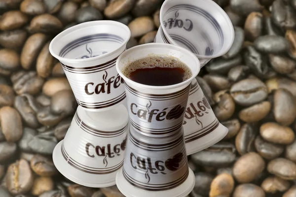 Πλαστικά ποτήρια με κόκκους καφέ καφέ φόντο — Φωτογραφία Αρχείου