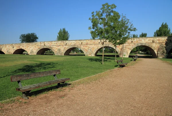 Ławka w parku z widokiem na zabytkowe most — Zdjęcie stockowe