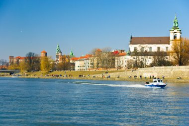 Vistula river with Wawel castle, St. Stanislaus Church at Skałka and Police motorboat in Cracow, Poland clipart