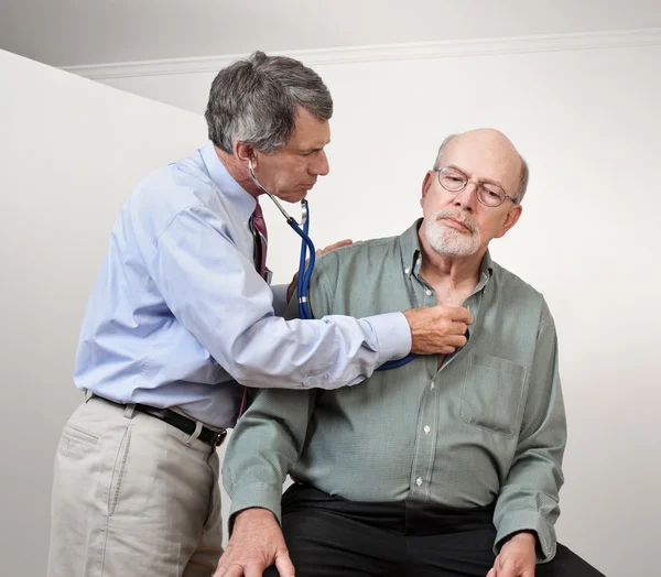 Läkare eller sjuksköterska lyssnar på äldre mannens hjärta och lungor — Stockfoto