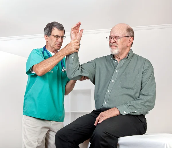 Arzt untersucht Augenzwinkern des Patienten mit Schmerzen im Arm — Stockfoto