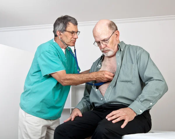 Läkare eller sjuksköterska lyssnar på äldre patientens hjärta och lungor — Stockfoto