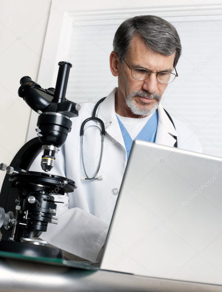 Doctor Analyzing Data at Laptop Computer and Microscope