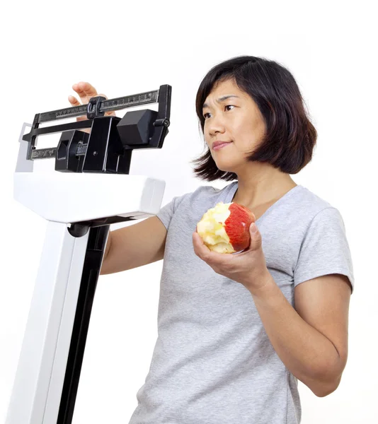 Kobieta z jabłkiem na skali martwi się o wadze zdobyć — Zdjęcie stockowe