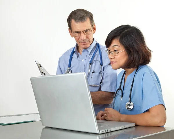 Доктор и медсестра за портативным компьютером — стоковое фото