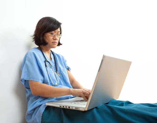 Kobieta lekarz lub pielęgniarka w komputerze przenośnym, w pozycji siedzącej — Zdjęcie stockowe