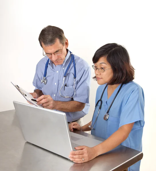 Arts en verpleegkundige herziening van informatie voor de patiënt op laptop berekenen — Stockfoto