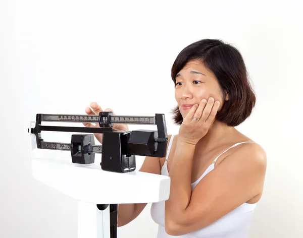 Vrouw met een gewicht van zichzelf op gewicht schaal — Stockfoto