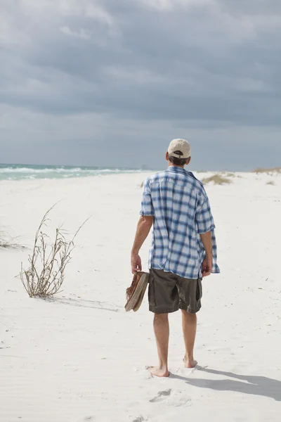 stock image Relaxed Man Walking on a Beautiful Beach Carrying Shoes