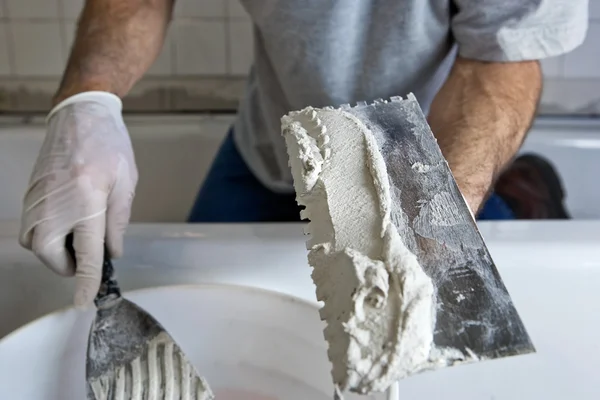 Man aan het werk met Troffel en mortel plavuizen, een badkamer muur — Stockfoto
